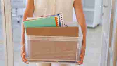 Woman with ADHD carrying box of things out of office after being fired