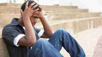 Man with ADHD sitting by steps with hands on head dealing with anger issues
